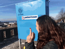 a woman giving the middle finger in front of a lambertsson sticker