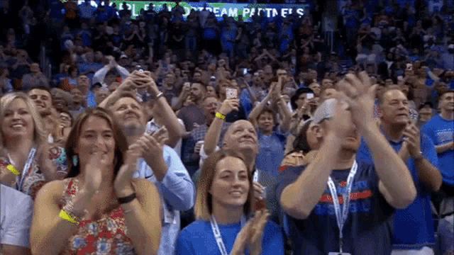 a crowd of people are applauding in front of a sign that says team partners 