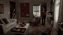 a woman standing in a living room with a couch and chairs