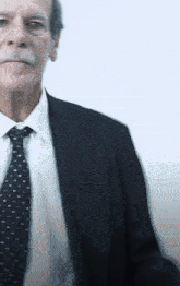 a man with a mustache wearing a black suit and tie