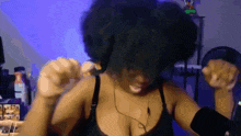 a woman in a black bra is dancing in front of a blue wall