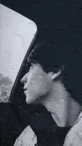 a man in a car looking out the window with rain drops on it