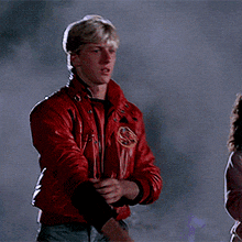 a man wearing a red leather jacket with a yellow emblem on the front
