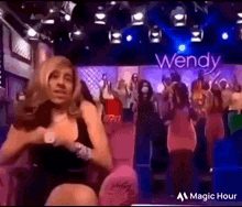 a woman in a wig is dancing in front of a sign that says wendy .