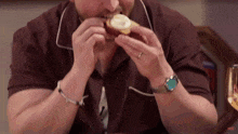 a man wearing a watch is eating a cupcake with the word shift on the bottom right