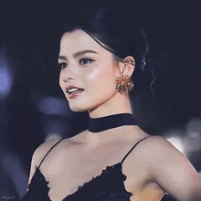 a woman wearing a choker and earrings is smiling for the camera with the name danny on the bottom right