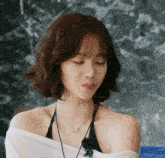 a woman wearing a white shirt and a black top with a necklace that says ' i love you ' on it