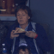 a man wearing a seattle seahawks hat eating a sandwich