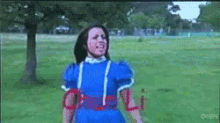 a girl in a blue dress is standing in a field