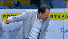 a man in a suit is pointing at something in front of a sign that says fortuna
