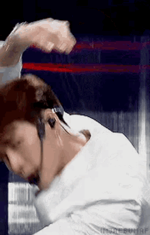 a man wearing headphones and a white shirt is standing in front of a boxing ring .