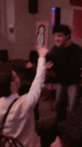a man in a black shirt holds up his arm in a room