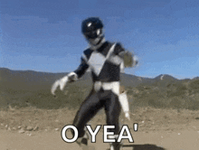 a black ranger from power rangers is dancing in the dirt in the desert .