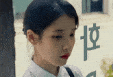 a woman stands in front of a window with chinese writing