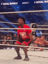 a man is squatting in a wrestling ring during a match .