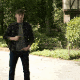 a man wearing a plaid shirt and jeans stands on a sidewalk
