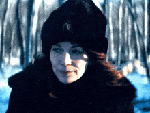 a woman wearing a fur hat and a fur coat stands in the snow