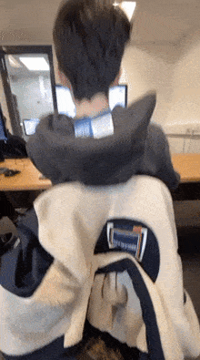 a man sitting at a desk with a sweatshirt on that says columbia on the back