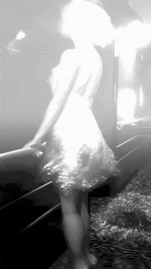 a woman in a white dress is standing on a staircase