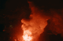 a large fire with smoke coming out of it at night