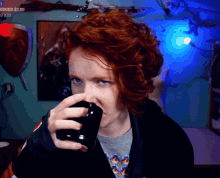 a woman with red hair is drinking from a black mug with the words edged $ 2.00 on the bottom