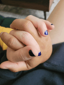 a close up of a person 's hand with blue and black nail polish