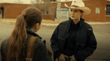 a woman in a cowboy hat is talking to another woman outside