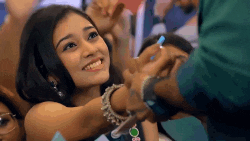 a woman is smiling while being held by a man in a crowd of people .