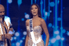 a woman in a colombia sash stands on stage