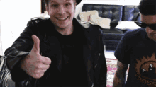 a man in a leather jacket is giving a thumbs up sign