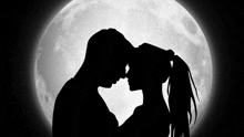 a silhouette of a man and woman kissing in front of the full moon