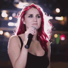 a woman singing into a microphone with red hair