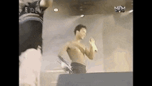 a shirtless man is holding a microphone on a stage .