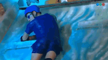 a man wearing a blue helmet and goggles is crawling through a pool