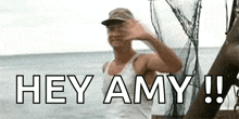 a man is standing on a boat in the ocean waving his hand and says `` hey amy '' .