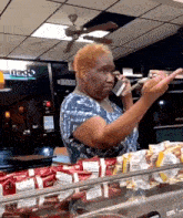 a woman talking on a cell phone in front of a display of doritos