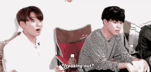 a couple of young men are sitting next to each other in a room .
