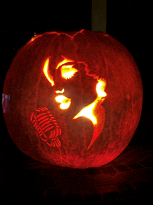a carved pumpkin with a woman 's face and a microphone carved into it