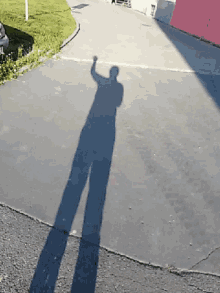 a person 's shadow is cast on a concrete surface