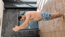 a shirtless man in blue swim trunks is doing push ups