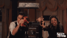 a man and a woman are playing with puppets in front of a camera that says heart & me on the bottom