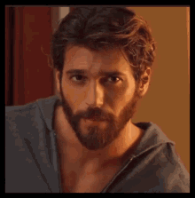 a man with a beard and long hair is wearing a blue shirt .