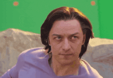a man wearing headphones is sitting on a couch with a green background .