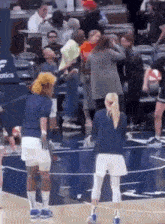 a group of people are standing on a basketball court with a referee .