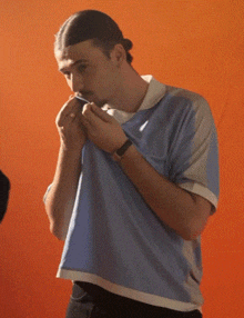 a man wearing a blue and white shirt is smoking a cigarette
