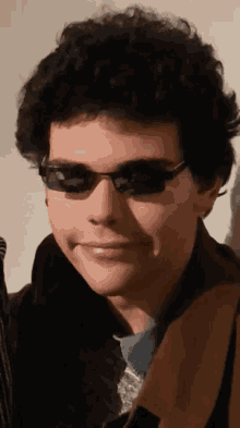 a close up of a man wearing sunglasses and a brown jacket