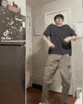 a man is dancing in front of a black refrigerator that says tiktok