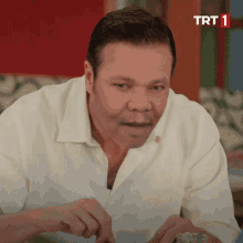 a man in a white shirt is sitting in front of a sign that says trt