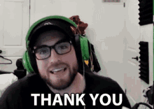 a man wearing glasses and headphones is giving a thank you sign .
