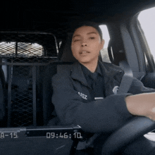 a woman in a police uniform is driving a car with the time 9:46